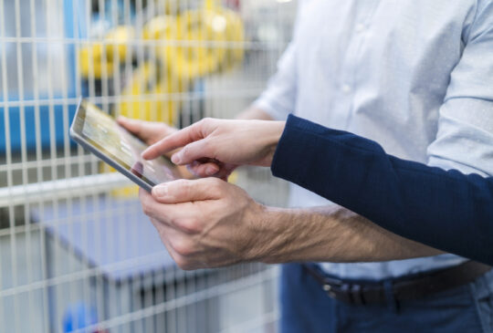Close-up of businessman and businesswoman using tablet in modern factory
