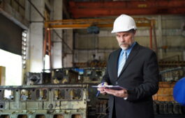 Factory manager or businessman and female engineer in factory. elegant man inspecting factory in industry plant background.
