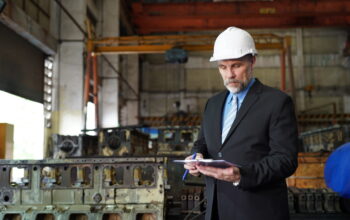 Factory manager or businessman and female engineer in factory. elegant man inspecting factory in industry plant background.