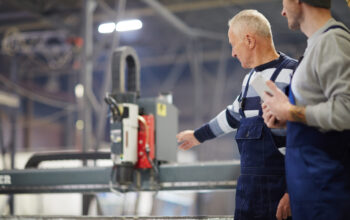Two professionals in workwear discussing engine system of new boat during work in factory