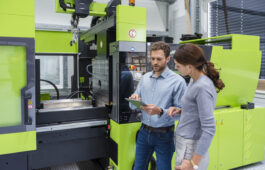 Colleagues in high tech company controlling manufacturing machines, using digital tablet
