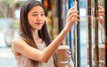 Asian young woman hand using smart mobile phone scanning the movie tickets machine for buy and get the coupon in department store,lifestyle and leisure,entertain and technology scanner concept